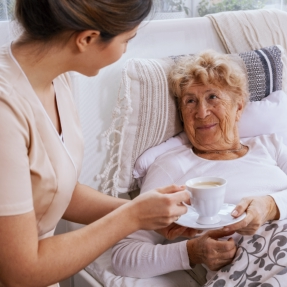 caregiver giving drink to the elderly